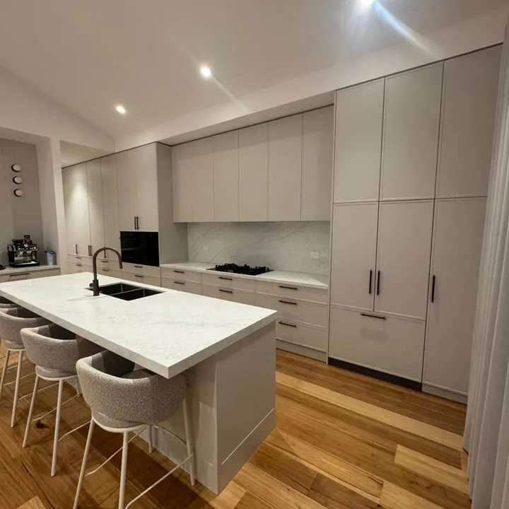 White kitchen with a stone-topped island and boucle stools