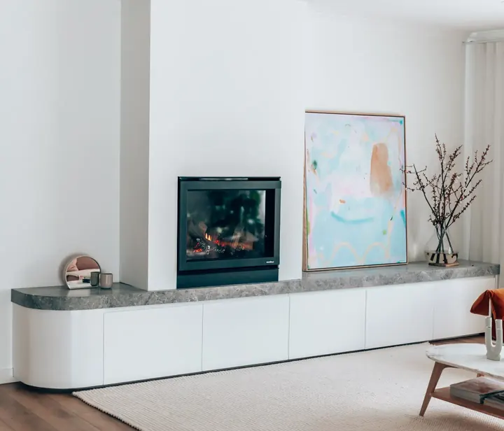 Curved white built-in unit with a fireplace and stone top